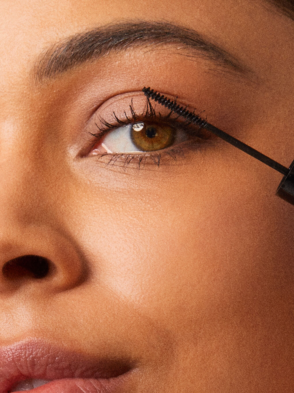 close up of brunette model applying detail oriented mascara